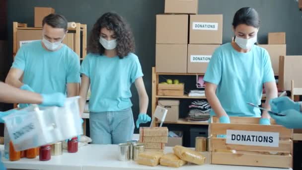 Группа Благотворителей Масках Перчатках Упаковывает Продукты Пожертвований Время Пандемии Концепция — стоковое видео