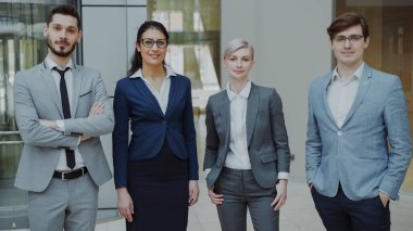 Modern ofis kapalı gülümseyen iş adamları grup portresi. Takım işadamları ve birlikte ayakta iş kadınları