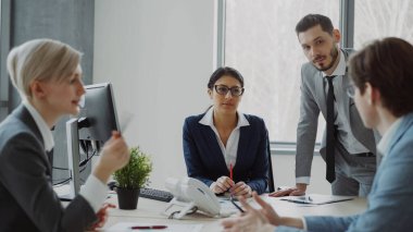 Modern ofis kapalı masada oturan kadın ve erkek arkadaşları ile konuşurken işkadını