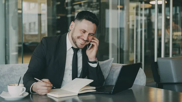 Szakállas Mosolygós Üzletember Laptoppal Okostelefonon Beszél Üzleti Információkat Modern Kávézóban — Stock Fotó