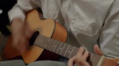 Arkadaşları evde dinlerken gitarist ve şarkı söyleyen yaratıcı melez adamın yakın çekimi. Müzik aleti ve gençlik kültürü konsepti.