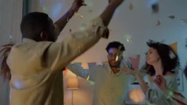 Mutlu genç arkadaşlar doğum günlerini evde dans ederek ve gece konfeti izleyerek kutluyorlar. Modern yaşam tarzı ve boş zaman aktivitesi konsepti.