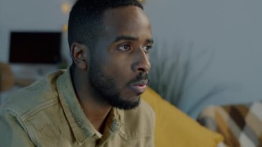Afro-Amerikan spor fanatiği TV 'de maç izliyor ve karanlık bir dairede bira içiyor. Modern yaşam tarzı ve olumlu duygu kavramı.