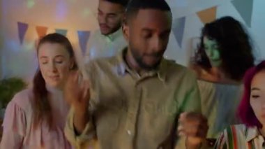 Afrikalı Amerikalı bir adam arkadaşlarıyla dans ediyor. Süslü bir dairede gece partisinin tadını çıkarıyor. Gençler müzik eşliğinde gülümsüyor..