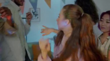 Geceleri heyecan verici bir parti sırasında neşeli arkadaşlarla dans eden modern bir genç kadın. Öğrenciler boş zamanlarında birlikte takılıyor..
