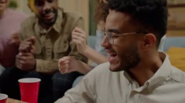 Mutlu bir öğrenci gitar çalarken, arkadaşları evde parti sırasında şarkı söyleyip gülerken. Müzik ve arkadaşlık kavramı.