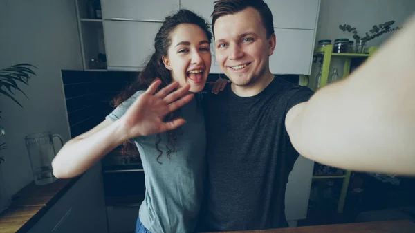 的观点拍摄的年轻快乐夫妇有在线视频电话与智能手机相机站在家里的厨房 — 图库照片