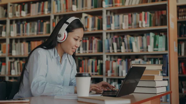 Красива Азіатська Студентка Великими Навушниками Сидить Столом Бібліотеці Працює Шкільному — стокове фото