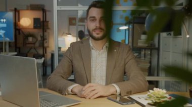 Hippi erkek öğrenci Üniversite Kütüphanesi sınavlarda için kapalı kitap okuyan sınıf arkadaşları ile hazırlarken dizüstü bilgisayar kullanan bardaklarda odaklanmak