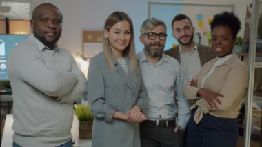İş adamlarının yavaş çekimde portresi. Çeşitli takımlar gece kurul odasında kameraya bakıp gülümsüyor. Erkekler ve kadınlar şık resmi kıyafetler giyiyorlar..
