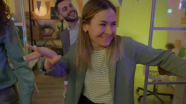 İş arkadaşlarıyla dans eden sarhoş kadın karanlık ofiste şirket partisinde eğleniyor. Modern yaşam tarzı ve boş zaman aktivite konsepti.
