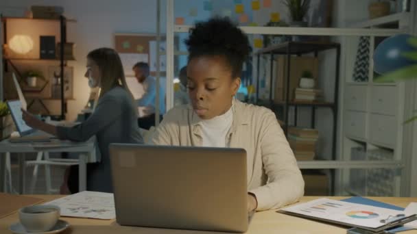 厌倦了的非洲裔美国女商人使用笔记本电脑 晚上在黑暗的办公室里工作时感到压力很大 人与过度工作概念 — 图库视频影像