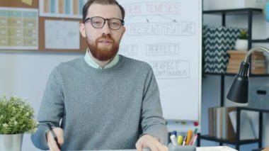 İngilizce öğretmeni online ders sırasında gramer açıklarken grafiği grafikle göstererek konuşuyor ve kameraya bakıyor. Sanal eğitim ve e-öğrenme kavramı.
