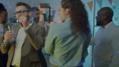 Şirket partisinde iş arkadaşlarıyla dans eden mutlu genç bir bayan. Ofiste elinde bir kadeh şampanya tutuyor. Gençlik ve özel durum kavramı.