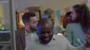 İş partisinde iş arkadaşlarıyla eğlenen Afrikalı Amerikalı adamın ağır çekimde portresi. Modern yaşam tarzı ve kurumsal etkinlik kavramı.