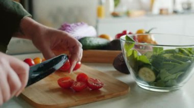 Keskin bıçaklı salata kullanarak tahta kesme tahtasından taze domatesler kesen kadın ellerinin yakın çekimi. İnsanlar ve aşçılık kavramı.