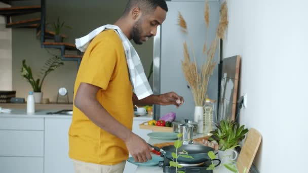 Radosny Afroamerykanin Robi Śniadanie Tańczy Stojąc Obok Kuchenki Elektrycznej Kuchni — Wideo stockowe