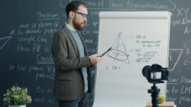 İnternet günlüğü için eğitim videosu kaydeden blogger sınıfta geometriyi açıklıyor ve kameraya bakıyor. Vlog yazma ve uzak eğitim kavramı.