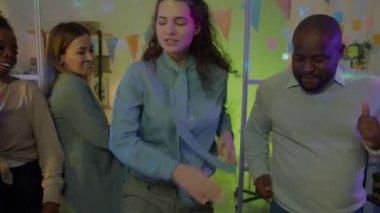 İş adamlarının ve iş kadınlarının gece ofiste dans edip kurumsal partinin tadını çıkarmalarının yavaş çekimleri. Halk ve gençlik kültürü kavramı.