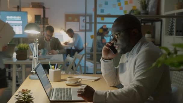 Rušný Africký Podnikatel Mluví Mobilním Telefonu Při Pohledu Obrazovce Notebooku — Stock video