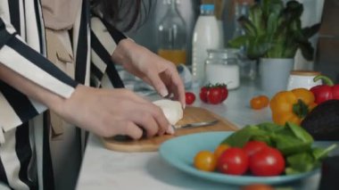 Kadın eli yakın çekim, yemek kesme, evde yemek hazırlama, masada yemek. Sağlıklı beslenme ve lezzetli öğle yemeği konsepti.