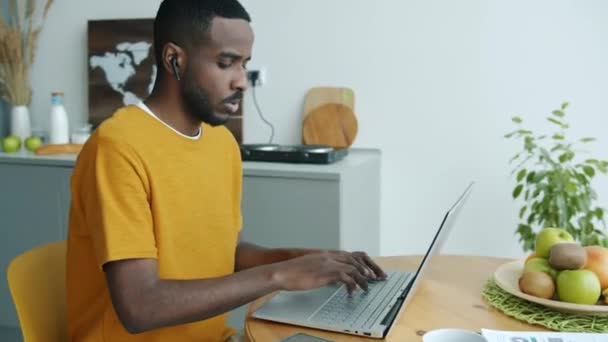 Αφροαμερικάνος Που Δουλεύει Από Σπίτι Χρησιμοποιώντας Λάπτοπ Και Ακουστικά Κατά — Αρχείο Βίντεο