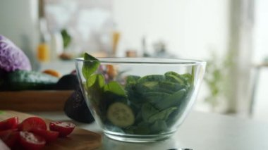 Kadın yemek pişirirken, kadın eli kesilen domatesleri sebze salatasıyla birlikte kaseye koyar. Diyet ve beslenme konsepti.