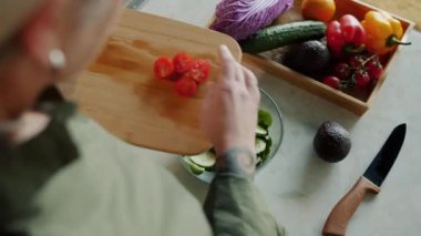Hanımların el manzarası, sulu domatesleri sebze salatasıyla kaseye koyuyor ve evde yemek pişiriyor. İnsanlar ve aşçılık kavramı.