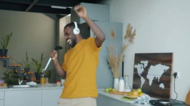 Mutlu adam hayali bir mikrofonda dans edip şarkı söylüyor. Mutfakta eğleniyor. Genç adam kablosuz kulaklıkla müzik dinliyor..