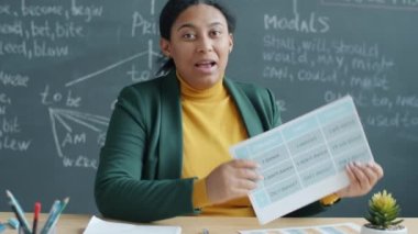 Uzak derste öğrenciyle İngilizce öğreten modern çevrimiçi öğretmen portresi. Afro-Amerikalı kadın kameraya bakıyor ve grafikleri gösteriyor..