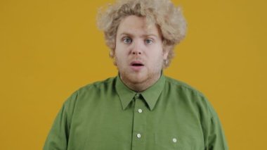 Umutsuz ve korkmuş genç bir adamın portresi sarı arka planda duruyor ve yalvarıyor ve susuyor. Yoğun duygular ve korku kavramı.