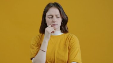 Zeki bir kadının portresi. Sonra parmağını kaldırıp, sarı arka plandaki kameraya bakıp gülümsemek.