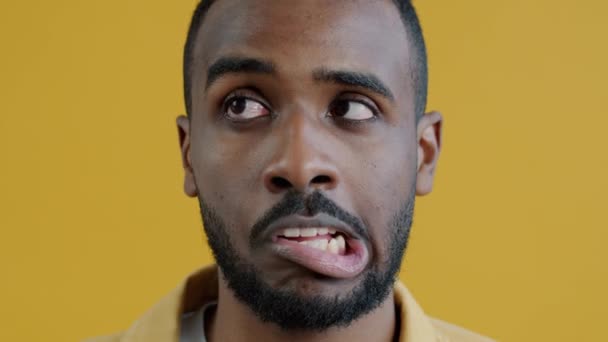 面白いアフリカ系アメリカ人の男の肖像画黄色の背景に顔を作って目を転がす 遊び心のある若者と表情のコンセプト — ストック動画