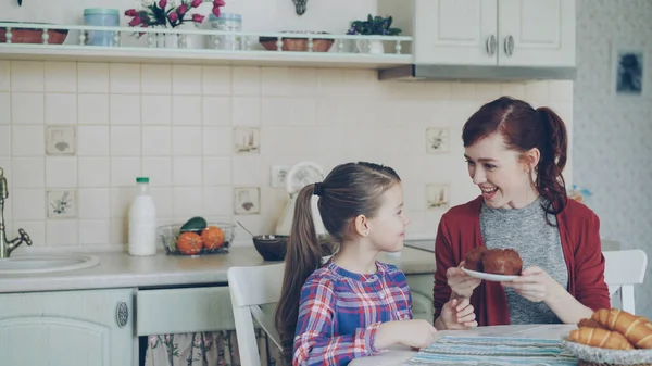 Young Happy Mother Bringing Tasty Muffins Her Cute Daughter Sitting — Stock Photo, Image
