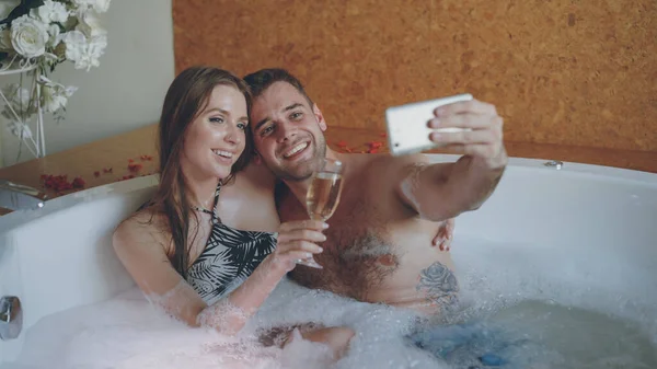 여자와 그녀의 샴페인 욕조에 스마트폰 Selfie를 취하고 그들은 카메라를 — 스톡 사진