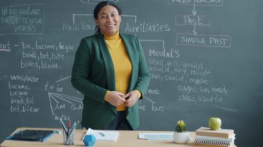 Sınıfta çalışan İngilizce öğretmeni uzaktaki derste konuşuyor ve kameraya bakıyor. Sosyal izolasyon ve modern eğitim kavramı.