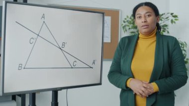 Afrika kökenli Amerikalı kadın portresi. Uzak derste geometri öğretiyor. Elektronik tahtayı işaret ediyor ve açıklıyor. Evden çalışma ve uzaktan eğitim kavramı.