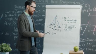 Çizelgeye işaret eden neşeli matematik öğretmeninin portresi ve sınıfta online ders vermek. Uzaktan eğitim ve üniversite kursu kavramı.