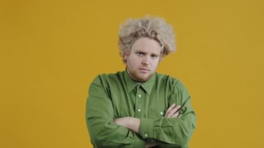 Yalnız bir adamın ağır çekim portresi üzgün bir suratla ayakta duruyor sonra parlak konfetileri izliyor ve sarı arka planda gülümsüyor. İnsanlar ve eğlence konsepti.