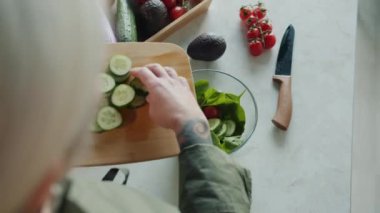 Kadın eli omzunun üstünden salata hazırlarken evde, mutfakta sebzeleri kaseye koyarken. Yemek ve vejetaryen diyet konsepti.