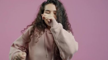 Pembe arka planda dans eden mutlu kız ve gülümseyen müziğin yavaş çekim portresi. Tasasız gençlik ve eğlence konsepti.