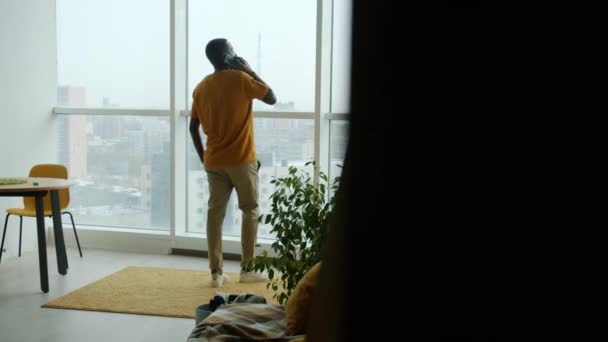 Афроамериканец Говорящий Мобильному Телефону Идет Домой Смотрит Панорамное Окно Коммуникации — стоковое видео