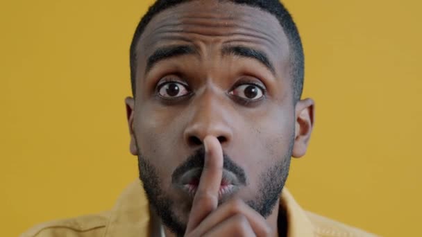 アフリカ系アメリカ人の親密な肖像画は 黄色の色の背景に沈黙を求めて 額のシャッシングで唇に触れる 人と表現の概念 — ストック動画