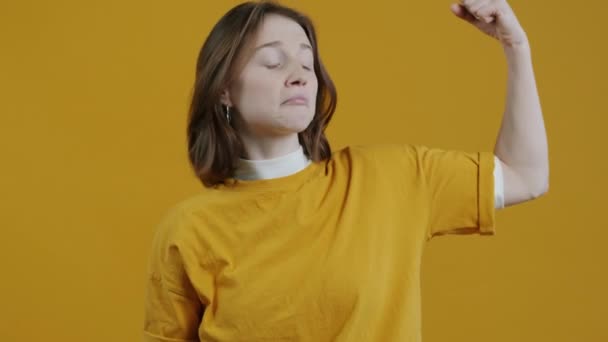 Zpomalený Portrét Legrační Dívky Demonstrující Biceps Dívající Kameru Žlutém Pozadí — Stock video