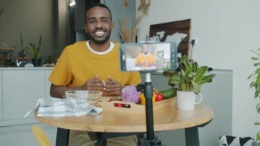 Modern mutfakta akıllı telefon kamerasıyla sebzeler hakkında video kaydeden yemek blogcusu. Sosyal medya ve sağlıklı yaşam tarzı kavramı.