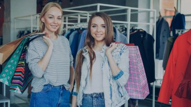 Güzel genç kadın portresi ile lots-in lüks Bayan giyim butik ellerinde kağıt torbalarda bekliyoruz. Moda Giyim, çanta, Ayakkabı ve baloons arka planda.