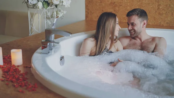 年轻的迷人的人拥抱和谈论在热鼓泡浴缸与泡沫在现代温泉 浪漫的关系 谈话和健康概念 — 图库照片