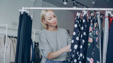 Sarışın kız moda giysiler içinde butik seçmektir. O güzel giysiler ile seyir ve polka noktalı elbise raylar, kalitesi ve uzunluğu inceleyerek alarak.