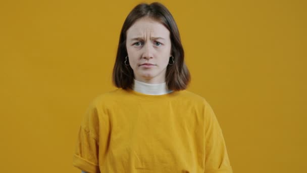 不幸な女の子のポートレートは ブラブラブラジャーをジェスチャーし 黄色の背景に迷惑とカメラを見て コミュニケーションと表現の概念 — ストック動画