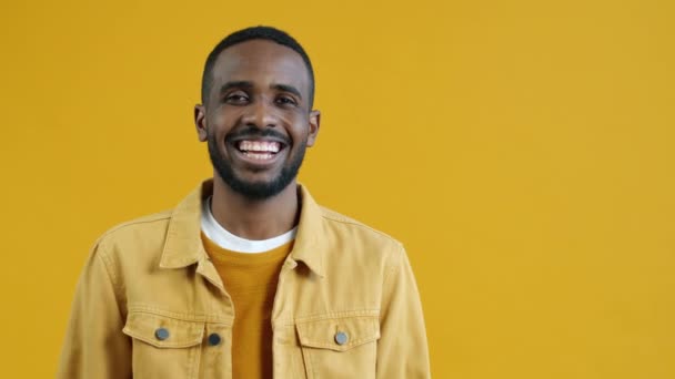 Retrato Hombre Afroamericano Feliz Apuntando Hacia Lado Riendo Sobre Fondo — Vídeo de stock